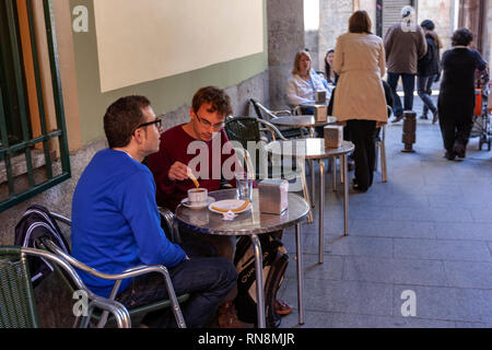 Young man wetting a churro with chocolate in the typical Chocolatería San Ginés, Chocolate Cafe, Pasadizo de San Ginés,, Madrid, Spain Stock Photo