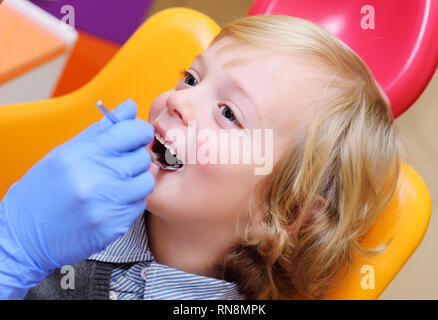 smiling baby boy with blond curly hair in dental chair. Stock Photo