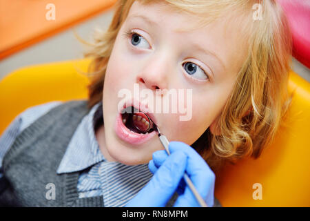 smiling baby boy with blond curly hair in dental chair. Stock Photo