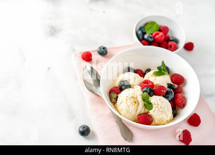 Close up of vanilla ice cream with berries on white table Stock Photo