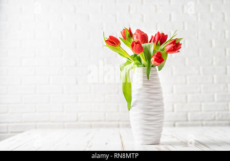 Red tulips in a white vase against the white background Stock Photo