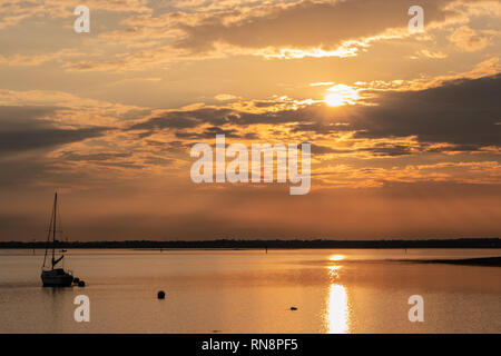 Sailing boat on calm waters during sunset Stock Photo