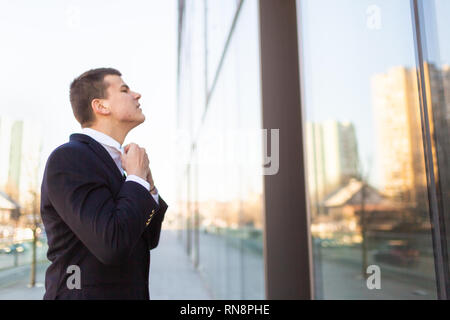 Young businessman looking himself in the glass mirror and adjusting collar. Preparation for job interview for business deal Stock Photo