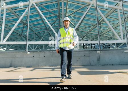 Male builder walking forward on the roof of construction site. Building, development concept. Stock Photo