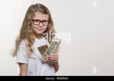 Smiling little girl with cash, white background, copy space. Money, Finance and the Concept of People Stock Photo