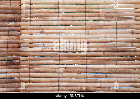 Old bamboo arranged horizontally with black tie rope. Wooden background. Stock Photo