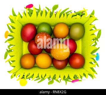 Stash of colorful Easter eggs, wax painted in a felt Easter basket on plain white background, isolated, top view Stock Photo