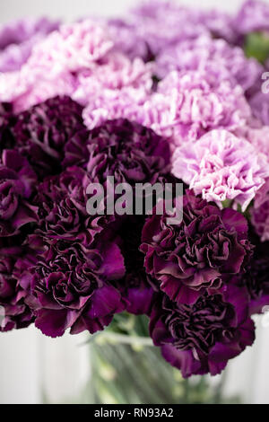 beautiful carnations flowers in a vase on a table . Bouquet of dark violet, purple and pink multicolor flower. Decoration of home. Floral texture Stock Photo