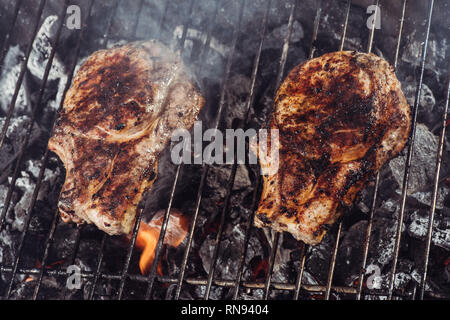 juicy delicious steaks grilling on barbecue grill grade with smoke Stock Photo