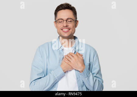 Grateful happy man holding hands on chest feeling appreciation Stock Photo