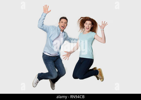 Happy excited  young couple friends jumping together isolated on background Stock Photo