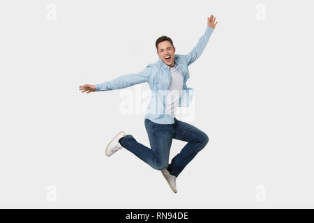 Happy cheerful young man jumping feeling joy isolated on background Stock Photo