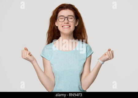 Happy overjoyed red-haired woman in glasses celebrating win success Stock Photo
