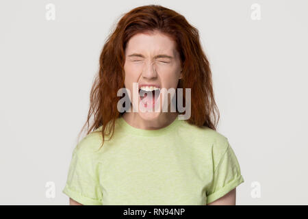 Angry stressed redhead woman screaming yelling loud isolated on background Stock Photo