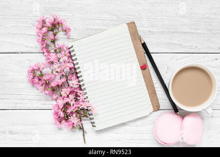 Creative layout made with spring cherry blossoming flowers, blank notepad, macaroons and coffee cup on white wooden background. Flat lay. top view. we Stock Photo