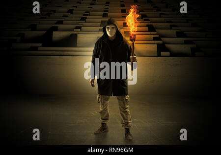 Ugly, aberrant man coming out from the labyrinth with burning flambeau on his hand  Stock Photo