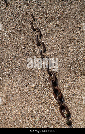 Chain partially buried in sand on the beach Stock Photo