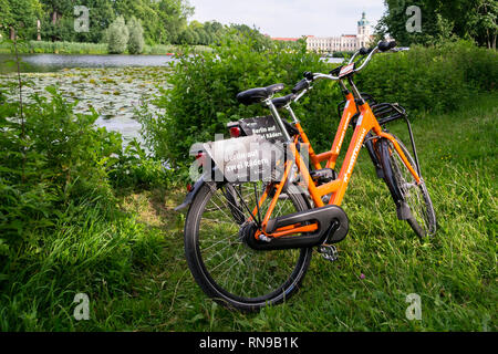 Berlin / Germany - 29 June 2018: Two Donkey Republic rented bicycles parked near a lake in the interior gardens of Charlottenburg Palace (Schloss Char Stock Photo