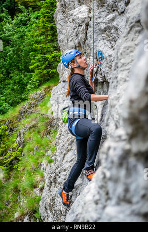 Beginner female climber on top rope, climbing a sport route near Sinaia town, in Bucegi mountains, Romania, on a chilly Spring day. Strong, active gir Stock Photo