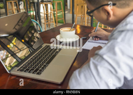 Side view of young man writing diary Stock Photo