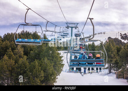 10 February 2019 - El Tarter, Andorra. Picture of skiers using chairlifts in the ski resort of El Tarter. Pinewood forest in the snowy mountains. Stock Photo