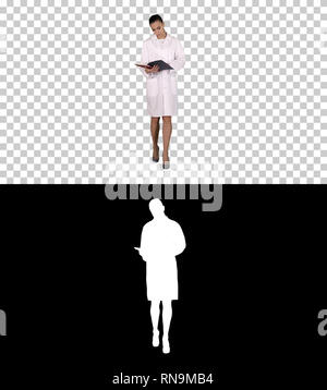 Young doctor woman reading documentation while walking, Alpha Channel Stock Photo
