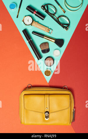 Top view of mascara, watch, bag, lipstick, bracelets, eyeshadow, blush, glasses and cosmetic brushes Stock Photo