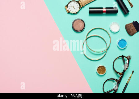 Top view of mascara, watch, lipstick, bracelets, eyeshadow, blush, glasses and cosmetic brushes Stock Photo