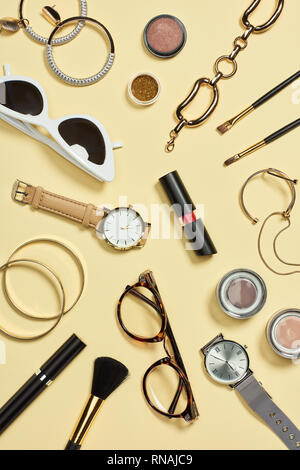 Top view of watches, lipstick, glasses, sunglasses, eyeshadow, blush, cosmetic brushes, bracelets, earrings and mascara Stock Photo