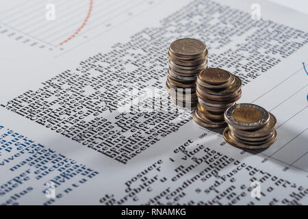 selective focus of coins stacks on text document with graphs Stock Photo