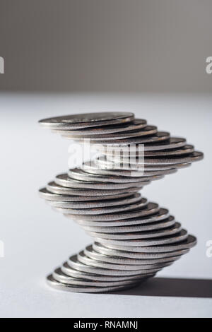 curved silver coins stack on blurred grey background Stock Photo