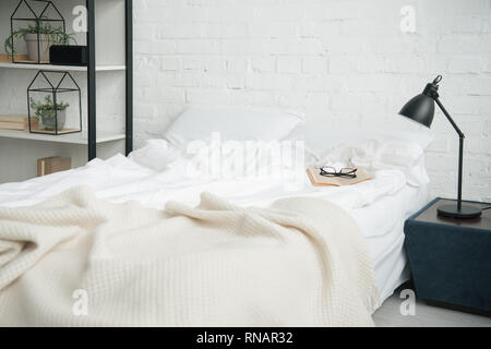 Bedroom with rack, white bed and lamp on nightstand Stock Photo