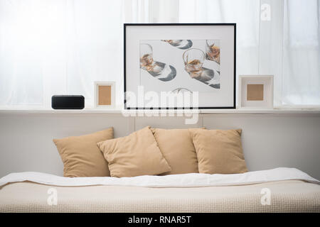 bedroom with brown pillows on bed, alarm clock, picture and photo frames Stock Photo