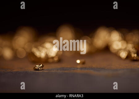 selective focus of small golden stone on grey and brown marble surface with blurred background Stock Photo