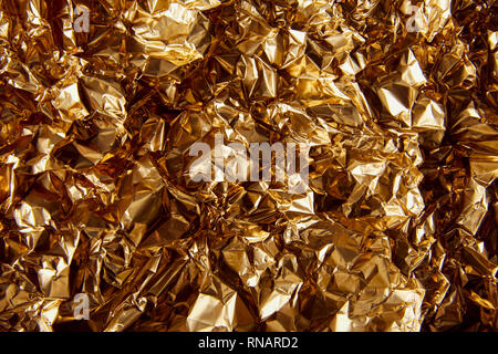 top view of crumpled golden foil with glares Stock Photo