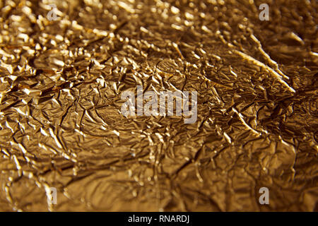 selective focus of sheet golden foil with glares Stock Photo