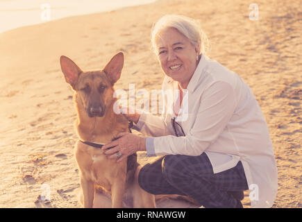 Portrait of beautiful widow older woman and german shepard dog enjoying its companion and love on beach in Benefits of animals Active Retirement lifes Stock Photo