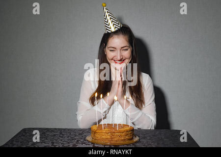 alone woman celebrates a holiday, he sits alone at a table with a cake and a candles Stock Photo