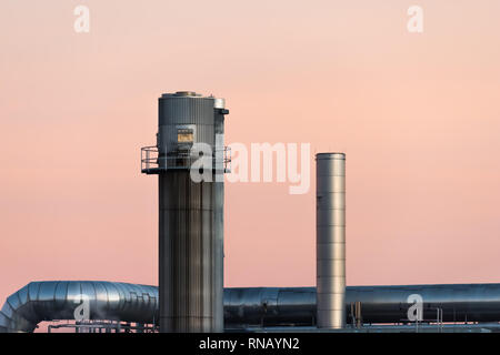 Two chimneys enjoy the clear sky at the horizon of the factory Stock Photo