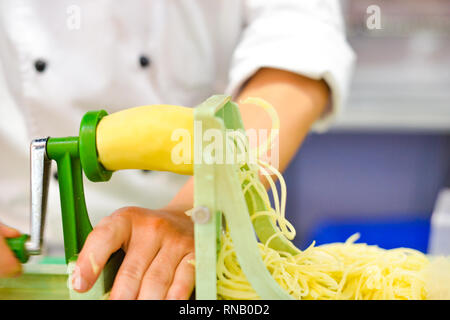 Vegetable Blade Spiralizer, Spiral vegetable slicer with potato spaghetti on table Stock Photo