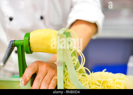 Vegetable Blade Spiralizer, Spiral vegetable slicer with potato spaghetti on table Stock Photo