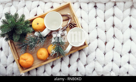 top view of two white cups with festive decorations, tangerines, pine cones, fir tree and pine branches on wooden board. copy space Stock Photo