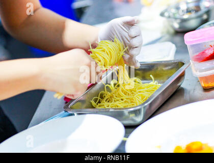 Chef cooking spaghetti in the kitchen, Chef putting Spaghetti to the plate Stock Photo