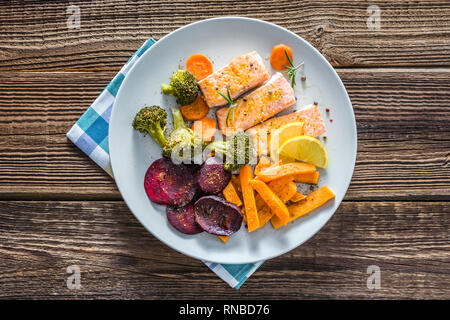 Appetizing diet food with grilled salmon and vegetable. Dinner on plate with fish fillet and cooked vegetables. Stock Photo