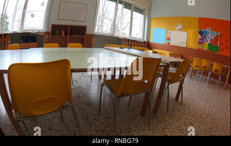 Inside a wide classroom of a Kingergarten with yellow chairs and small tables Stock Photo