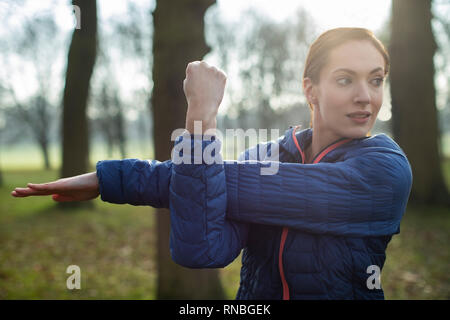 Woman Warming Up For Morning Exercise With Stretches In Winter Park Stock Photo