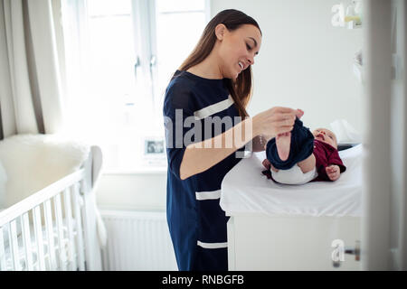 Mother In Nursery At Home Changing Baby Sons Daiper Stock Photo