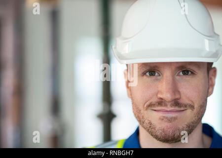 Portrait Of Male Construction Worker On Building Site Wearing Hard Hat Stock Photo