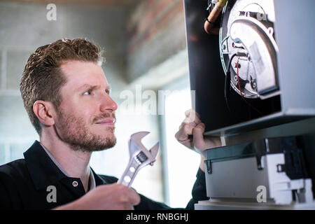 Male Heating Engineer With Adjustable Wrench Servicing Boiler Stock Photo