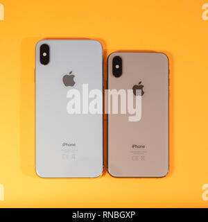 PARIS, FRANCE - SEP 27, 2018: Compare Apple Computers iPhone Xs and Xs Max as hero object on bright glamorous modern neon pop orange background - smartphone telephone Apple logo glass back Stock Photo